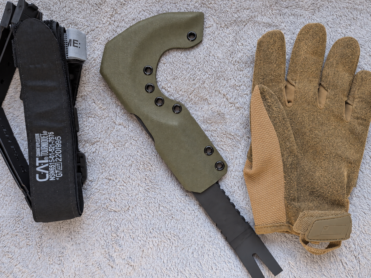 Olive Kydex sheath for NFORCE beside a glove