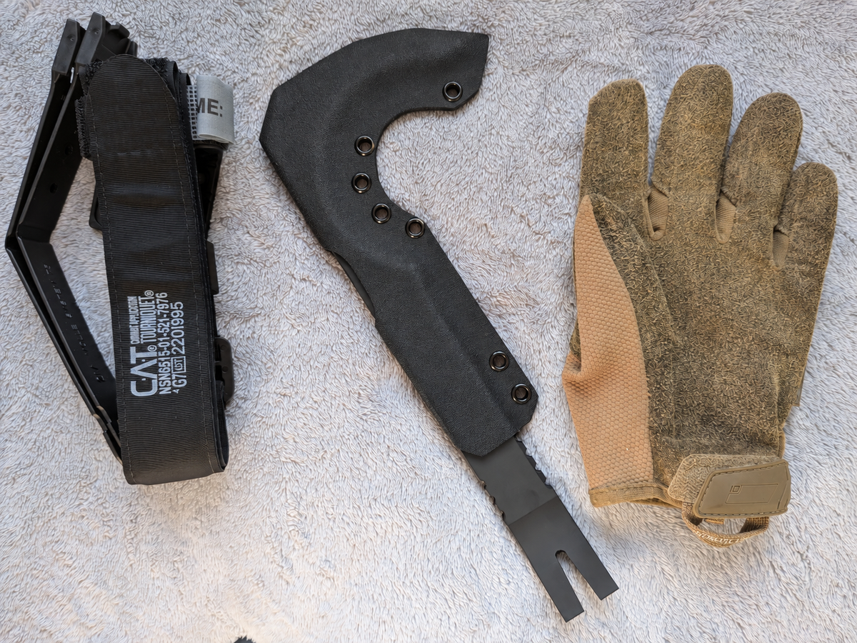 Black Kydex sheath for NFORCE beside a glove